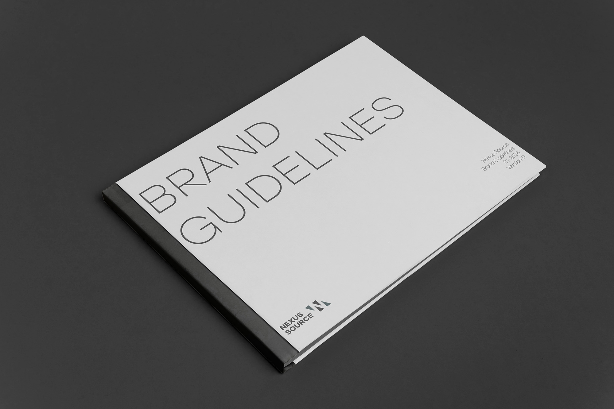 The printed Nexus Source Brand Guidelines book, cover up on a dark surface